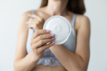 Woman holding absorbent pad for breast. Closeup, selective focus.