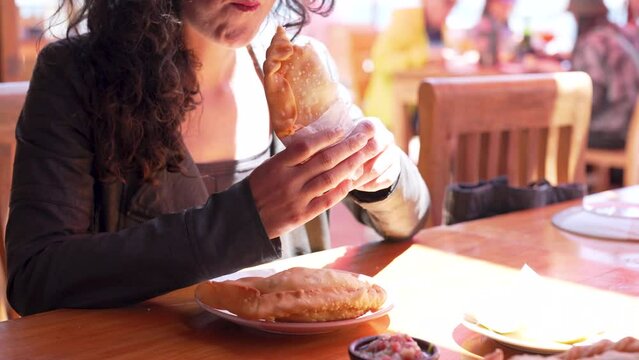 unrecognizable woman eating chilean fried seafood empanadas in restaurant