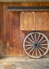 Obraz premium Wooden Wagon Wheel Leaning Against a Redwood Wall.
