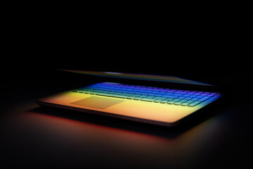 half closed laptop on dark table with colourful light reflection on keyboard