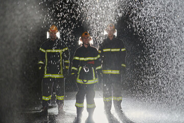 A group of professional firefighters marching through the rainy night on a rescue mission, their...