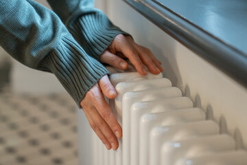 Woman touching radiator to feel temperature in modern apartment in winter cold season, hands...