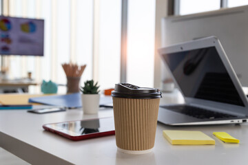 A paper coffee cup sits on the work desk.