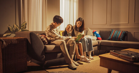Wide Shot of a Family of Three in the Living Room Using Technology: Korean Parents and Their Little Daughter Playing Games Together on a Digital Tablet Computer, Laughing and Having Fun