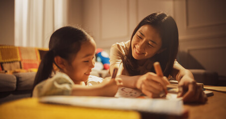 Portrait of a Korean Mother and her Cute Daughter Spending Evening Time Together in the Living Room...