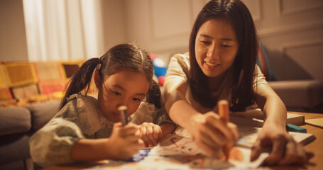 Portrait of Korean Mother Teaching her Little Daughter How to Draw in the Living Room at Home....