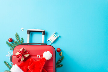 Santa's traveling plans include your party! Top view photo of a red suitcase, Santa's cap, fir...