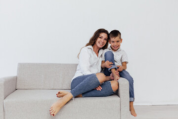 Fototapeta na wymiar mother and son sitting on the couch in a white room