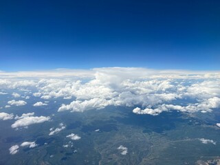 Fototapeta na wymiar Aerial view of a rural landscape enveloped in puffy clouds in blue sky background