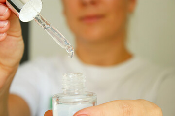 Close up of woman holding a bottle with skin serum for her face