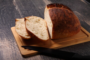 fresh  bread sliced on a board/ loaf of bread with knife