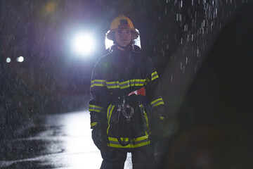 A determined female firefighter in a professional uniform striding through the dangerous, rainy...