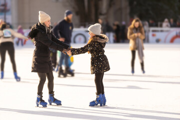 Adorable young mother with her daughter on the ice rink