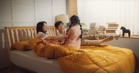 Happy Korean Family in the Morning: Active and Playful Child Running to her Parents' Bedroom to...