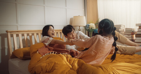 Happy Korean Family in the Morning: Active and Playful Child Running to her Parents' Bedroom to Wake Them Up. Excited Little Girl Forcing her Parents Out of Bed to Have a Fun Weekend Together