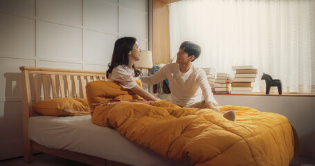 Beautiful Young Korean Couple Sleeping in Bed, Sun Shines on Them, They Look at Each Other and Greet New Sunny Day. Joyful Waking Up of Family of Two, Enjoying the Warmth of the Sun and Their Love