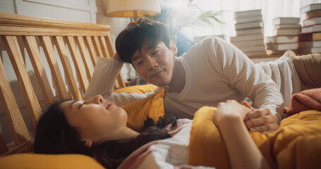 Beautiful Young Korean Couple Sleeping in Bed, Sun Shines on Them, They Look at Each Other and Greet New Sunny Day. Joyful Waking Up of Family of Two, Enjoying the Warmth of the Sun and Their Love