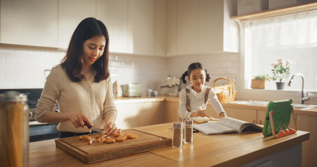 Portrait of a Korean Woman and her Daughter in the Kitchen at Home: Beautiful Mother Preparing for Cooking Lunch While Talking to her Cute Kid Who is Coloring Next to Her. Happy Family of Two