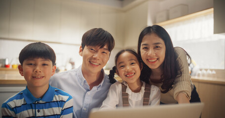 Portrait of Happy Korean Family Using Laptop Computer then Looking at the Camera and Smiling. Young Parents and Two Adorable Kids Watching Photos and Memories from their Last Trip Together - obrazy, fototapety, plakaty