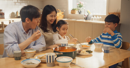 Happy Korean Family of Four Enjoying a Delicious Meal Together in Their Kitchen at Home. They are Sharing a Traditional Meal Made with Love and Care. Children Excited for Food - obrazy, fototapety, plakaty