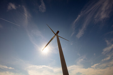  Wind farm turbine against sun and blue sky