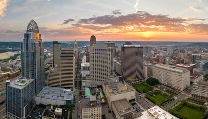 Cincinnati city in state of Ohio with brightly illuminated high skyscraper buildings in downtown district. American megapolis with business financial district at sunset - obrazy, fototapety, plakaty