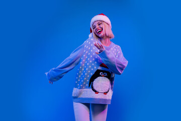 Photo of pretty adorable lady santa helper dressed ugly print xmas sweater having fun isolated blue color background