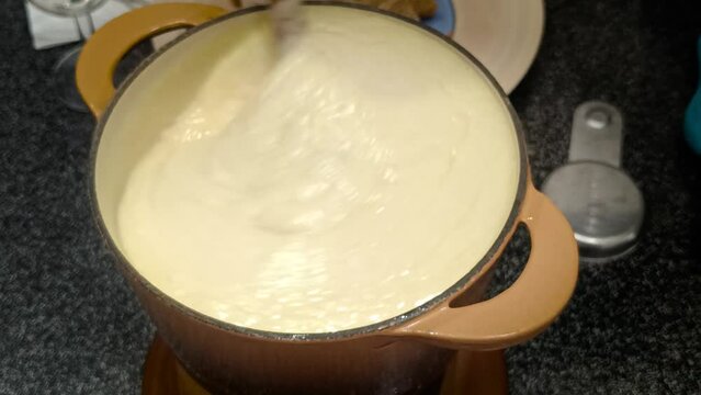 fondue savoyarde m&eacute;lang&eacute;e avec une cuill&egrave;re en bois