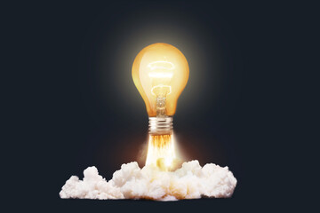 Creative light bulb rocket with blast and clouds takes off on a dark background, concept. Successful launch start up, creative idea. Think differently. Creative generator. Smart and thinking - obrazy, fototapety, plakaty