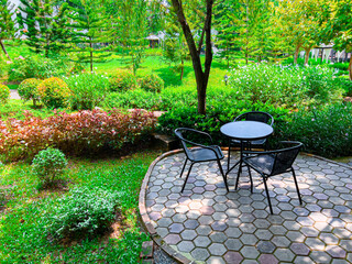Small black table and chair set That was placed in a garden full of grass. and refreshing green trees It is a resting spot that makes you feel refreshed.