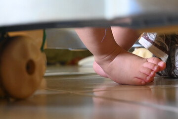 close up of a baby's feet moving on tiptoe using a baby walker that has lots of wheels.