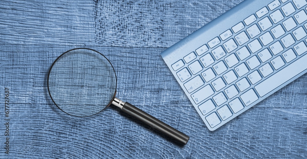 Poster the magnifying glass and computer keyboard on desk