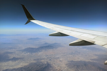 Obraz premium View through airplane window of commercial jet plane wing flying high in the sky. Air travelling concept