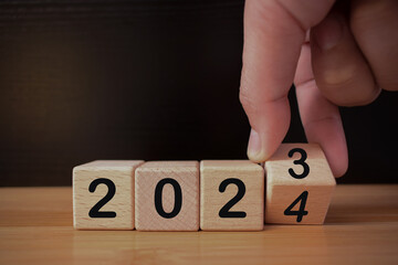 Hand flipping block 2023 to 2024 on table,
Merry Christmas and Happy New Year, 2024 new year idea concept,
resolution,plan, goal, motivation, reboot, countdown and New Year holiday concepts.