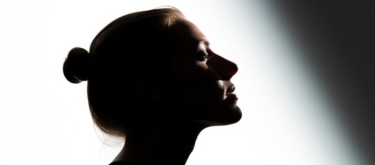  the silhouette of a woman's head is shown against a white background with the light coming through the window behind her.