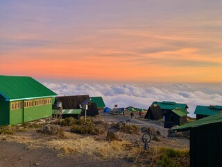 Horombo Huts on Mount Kilimanjaro with a sea of fluffy clouds around them under a colorful sky