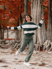 Obraz premium Lifestyle portrait of jumping woman in autumnal park. Stylish woman with emotions