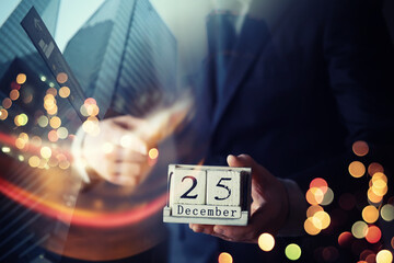 Businessman hand in a suit holding wooden cube with 25 december text . Resolution, strategy,...
