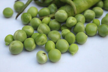 Closeup of fresh green pea seeds scattered on white background