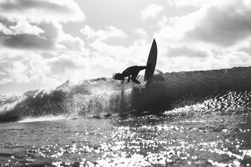 Beautiful shot of a surfer riding a wave in Portugal in grayscale