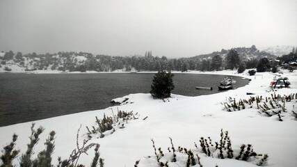 Field covered with a snow and trees with a river in the background