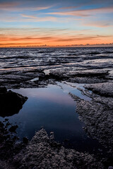 Hawaii Sunset - A beautiful orange sunset over the Pacific Ocean, reflecting in rock pools along the shore of a secluded Hawaiian beach