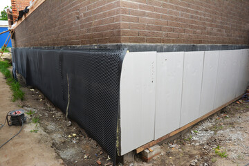 Brick house with foundation wall during insulation and waterproofing.