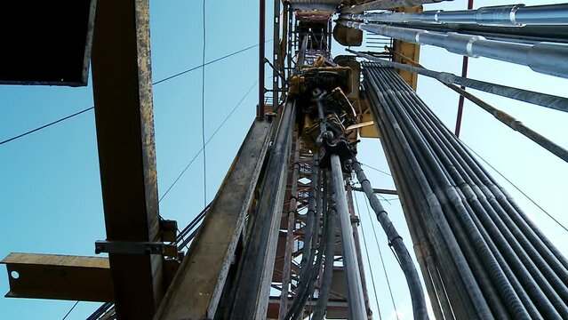 Drilling of the well.  Looking upwards inside the derrick. View of the drilling rig top with the drill pipe. 