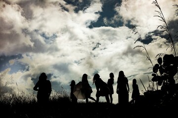 Low angle shot of silhouettes of a group of people under a bright sky