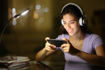 Happy woman in the night watching videos on phone