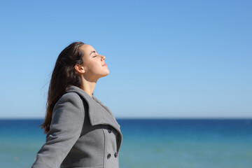 Woman in winter breathing fresh air on the beach
