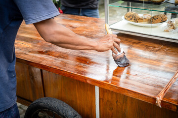 a carpenter varnishes a piece of wood with his hands