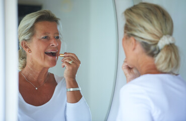 Obraz na płótnie Canvas Senior woman, lipstick and mirror in home with smile, thinking and beauty to start morning in retirement. Elderly person, makeup and product for lips, reflection and happy in bathroom for cosmetics