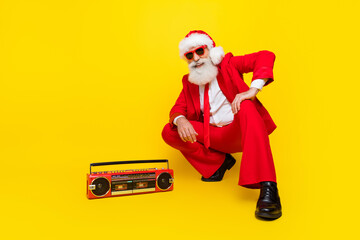 Full length photo of handsome funny claus wear red tux costume listening boom box music empty space isolated yellow color background © deagreez